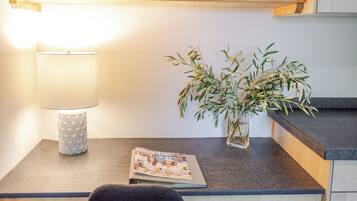 Een nachtkastje met een lamp, een klein vaasje met groene planten en een tijdschrift.