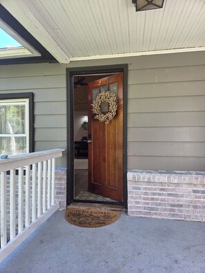A wooden front door with a wreath, a white porch railing, and a brick base. - Peaceful mountain cottage near Massanutten, JMU, National Park & Shenandoah Rive (Elkton)