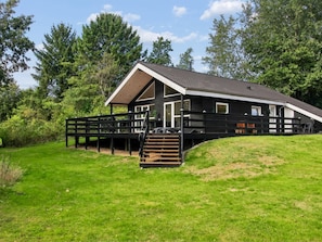 A two-story wooden cabin with a sloped roof, a deck, and a staircase leading to the entrance. - Vacation home "Elle" by Interhome (Toftlund)