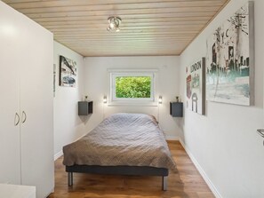 Quarto com cama, janela e obras de arte nas paredes.