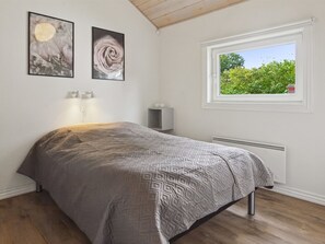 A bedroom with a bed, a window with a view of greenery, and two wall-mounted pictures. - Vacation home "Elle" by Interhome (Toftlund)