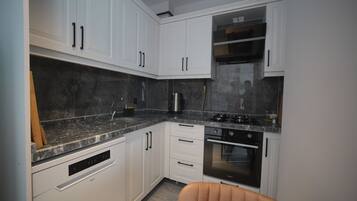 A modern kitchen with white cabinetry, a built-in oven, and a stainless steel range hood.