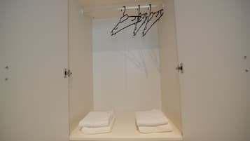 A bathroom with a white sink, two towels on the counter, and a towel rack with a towel hanging.