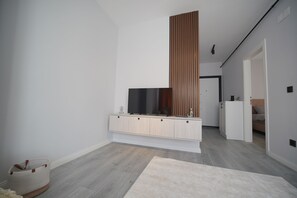 A modern bathroom with a wooden vanity, a large mirror, and a television.