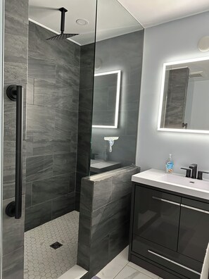 Un baño moderno con ducha, lavamanos y espejo.