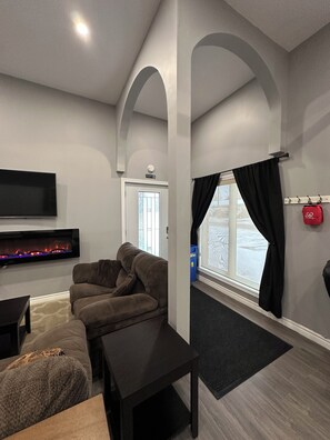Una sala de estar con una televisión de pantalla plana, un sofá, una mesa de centro y una chimenea.
