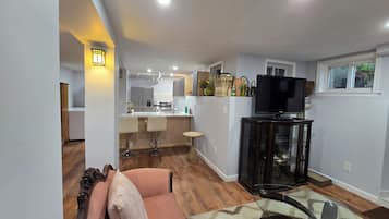 Una sala moderna con una mesa de centro de vidrio, un sofá con cojines y un televisor sobre un mueble.