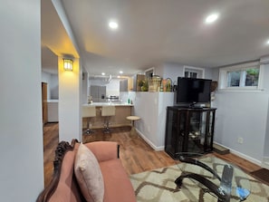 A modern living room with a glass coffee table, a sofa with cushions, and a television on a cabinet. - Historical 2BR APT in Brooklyn NY (Brooklyn)