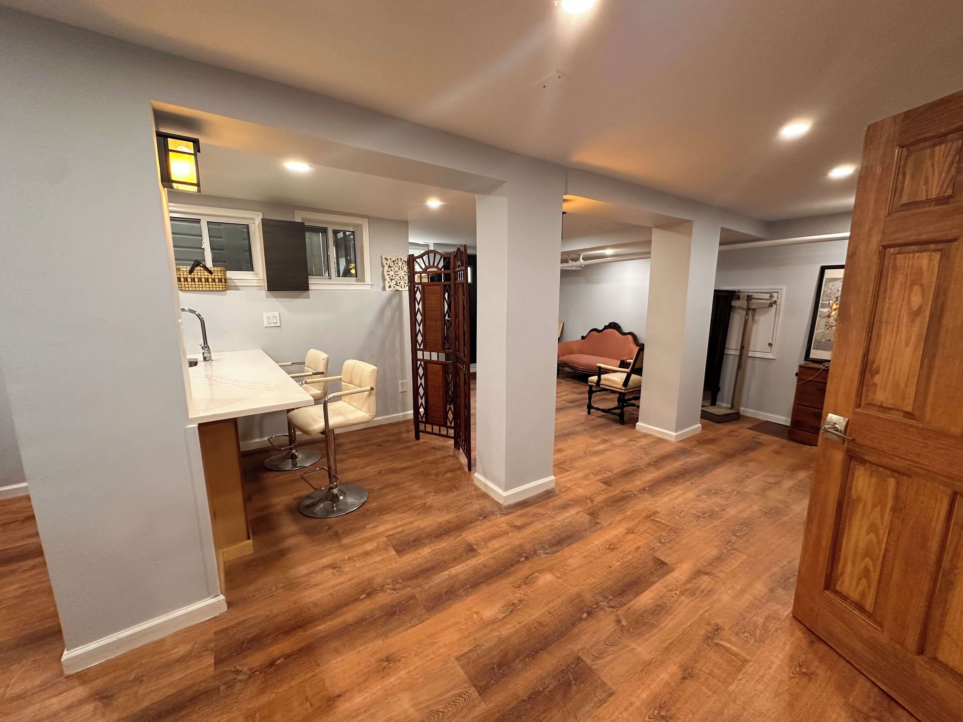A spacious room with a wooden floor, a dining area with a table and chairs, and a separate seating area with a sofa.