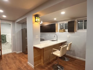A modern kitchen with a marble countertop, stainless steel appliances, and a bar area with bar stools. - Historical 2BR APT in Brooklyn NY (Brooklyn)