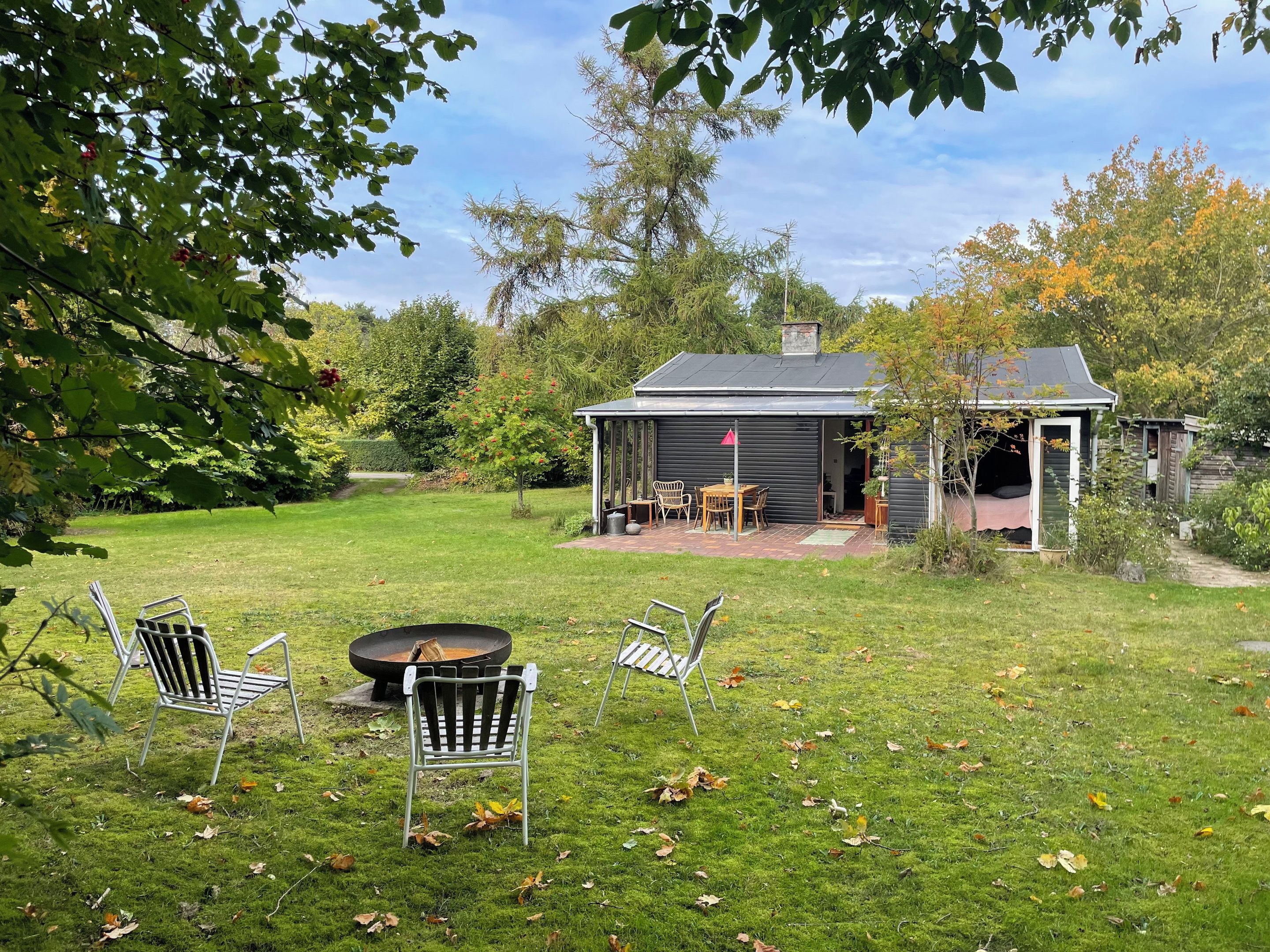 A backyard with a patio, a fire pit, and outdoor seating.