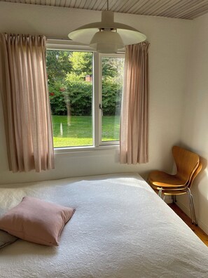 Une chambre à coucher avec un lit, une chaise et une fenêtre avec des rideaux.