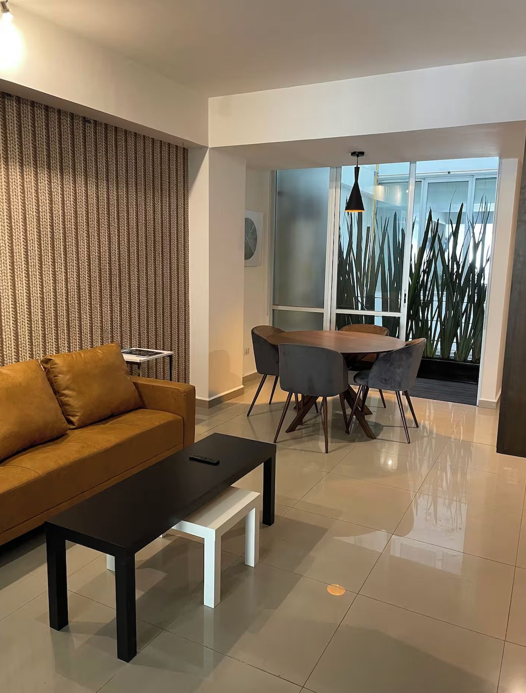 A modern living room with a sofa, coffee table, and dining area.
