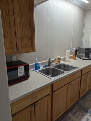 A kitchen with wooden cabinets, a stainless steel sink, a microwave, and a toaster. - Cozy Flat, Super Central Location (Pensacola)