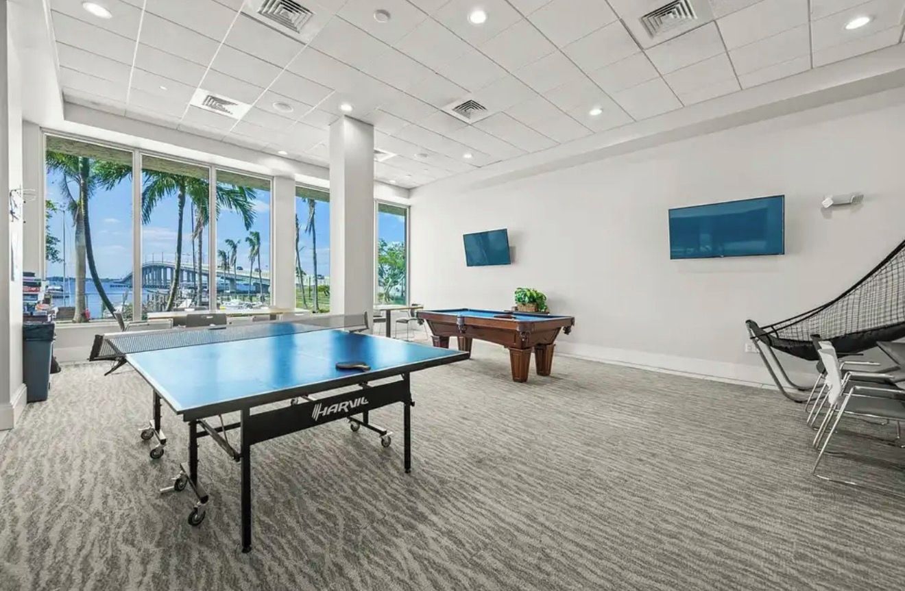 Een ruime kamer met een pooltafel, een tafelvoetbaltafel en een pingpongtafel.