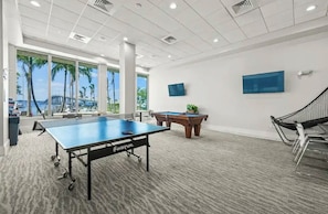 A spacious room with a pool table, a foosball table, and a ping pong table. - Cozy 1-bedroom condo downtown Fort Myers overlooking the Caloosahatchee River. (Fort Myers)
