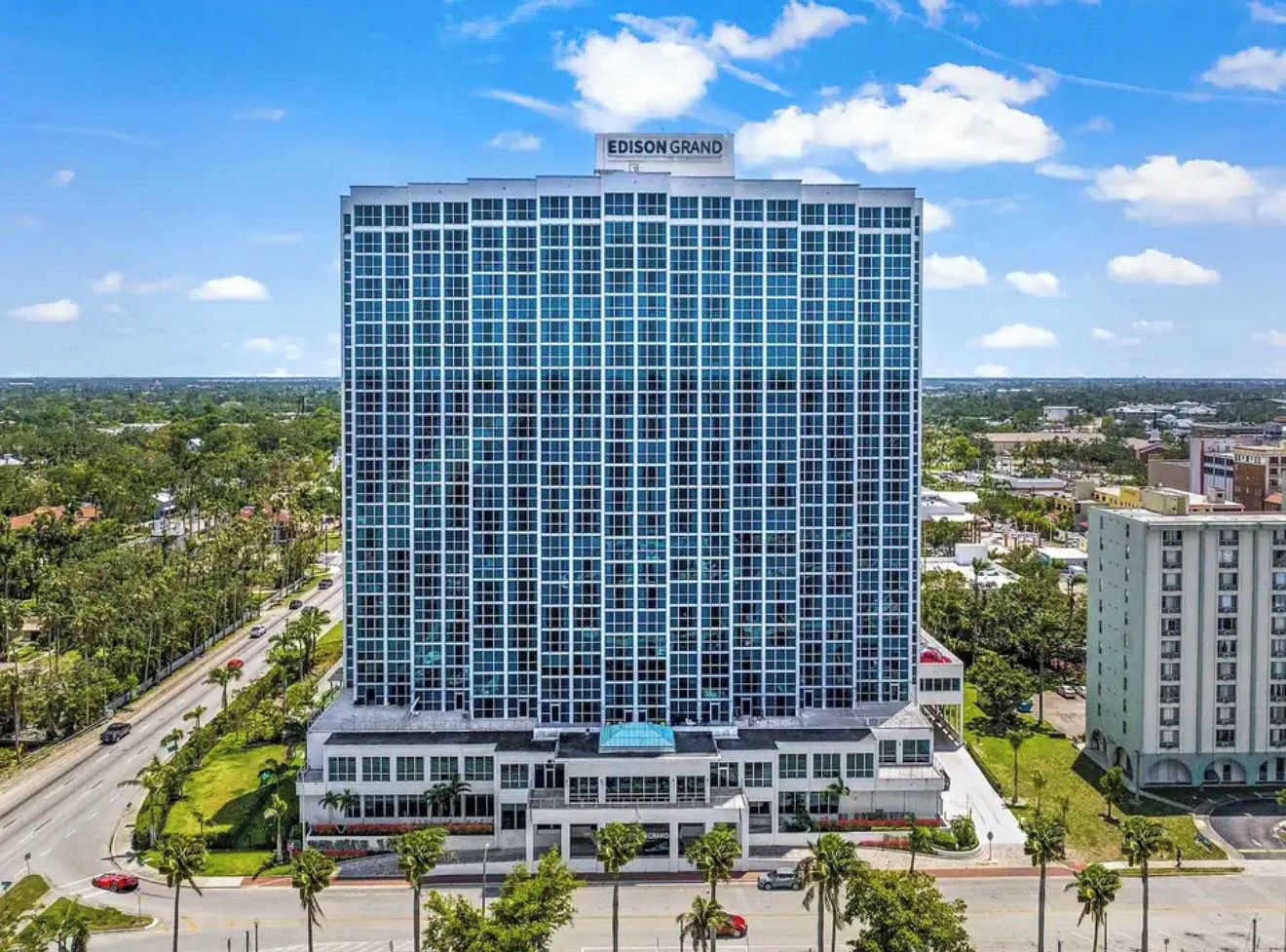 A high-rise hotel with a modern glass facade, named 'EDISON GRAND,' featuring a prominent sign at the top.