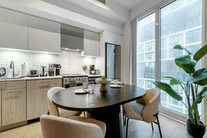 A modern kitchen with a dining area, featuring a large window and a potted plant. - Downtown 3BR, Balcony & City Views (Toronto)