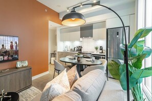 Ein modernes Wohnzimmer mit einer Couch, einem Esstisch und einem Fernseher.