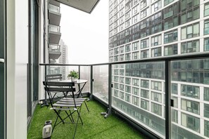 Ein Balkon mit Tisch, Stühlen, einem Blumentopf und Blick auf hohe Gebäude.