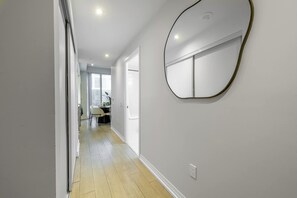 Ein Flur mit Holzboden, einem runden Spiegel an der Wand und einer Tür zu einem Zimmer mit Schreibtisch und Stuhl.