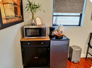 A kitchenette with a microwave, a small refrigerator, a coffee maker, and a basket of snacks. - Private King Suite 4-Min Walk to Wilton Drive (Wilton Manors)