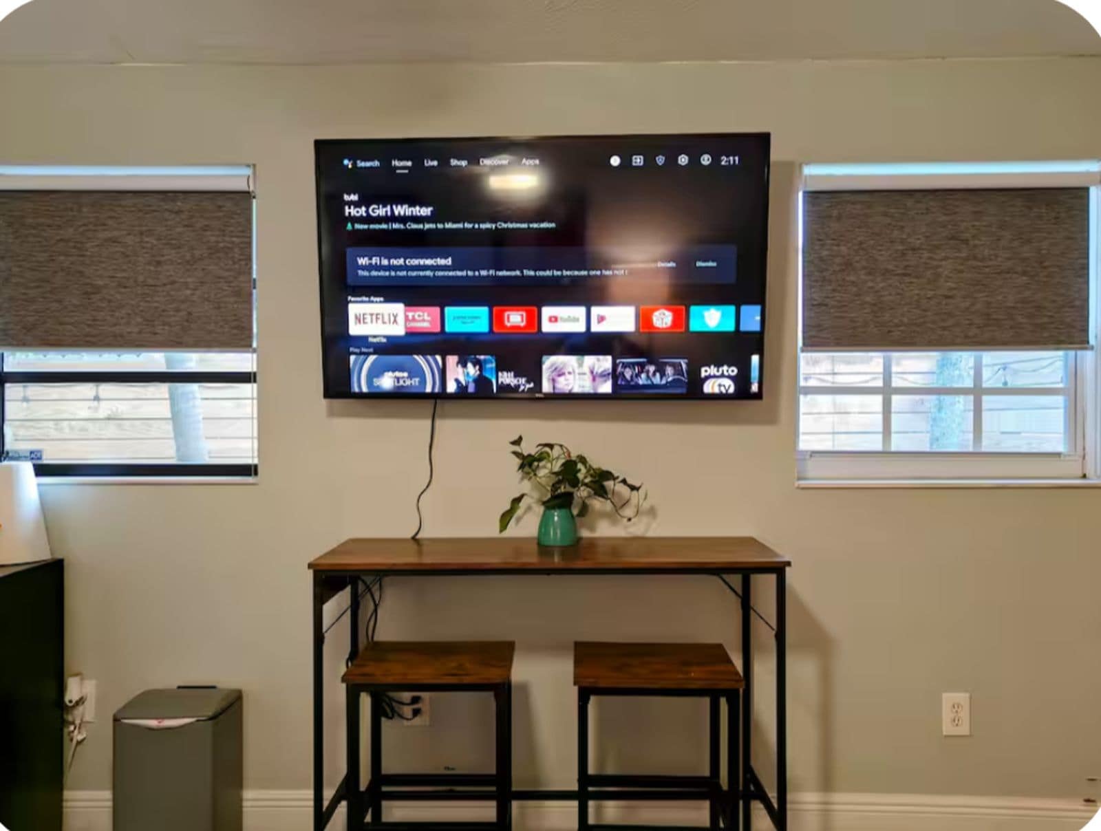 Un televisor de pantalla plana montado en la pared muestra una interfaz de servicio de streaming con varios íconos de aplicaciones.