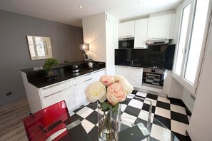 A modern kitchen with white cabinets, a black countertop, and a checkered floor. - New Listing (Bordeaux)
