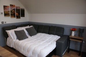 A bedroom with a bed, pillows, a bedside table with a lamp, and wall art.
