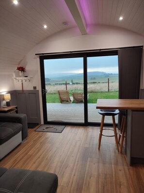 A modern interior with a sliding glass door leading to an outdoor area, a wooden dining table, and a sofa.