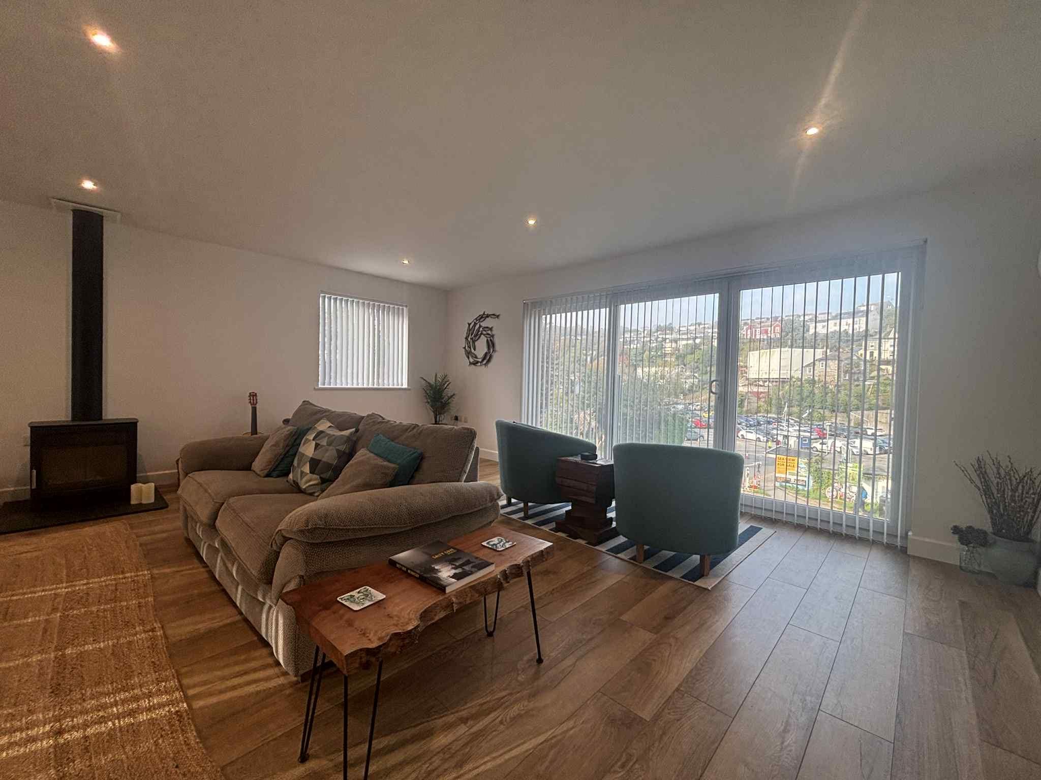Un salon comprenant un canapé, des fauteuils, une table basse, une cheminée et de grandes fenêtres offrant une vue sur la ville.