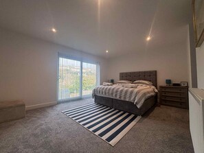 Un dormitorio con una cama grande, una ventana con persianas, un radiador y una alfombra a rayas.
