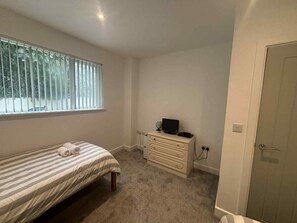A bedroom with a single bed, a dresser, a globe, and a television. - Newly refurbished modern house with parking, ideally situated & sleeps up to 8! (Mevagissey)