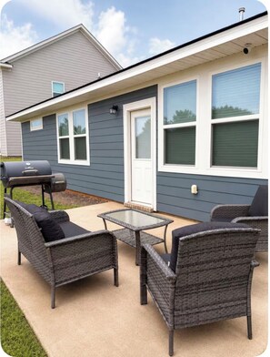 An outdoor patio with wicker furniture, a barbecue grill, and a glass table. - Auburn Game Day Retreat 3BR, Sleeps 6, 5 Min to Campus (Auburn)