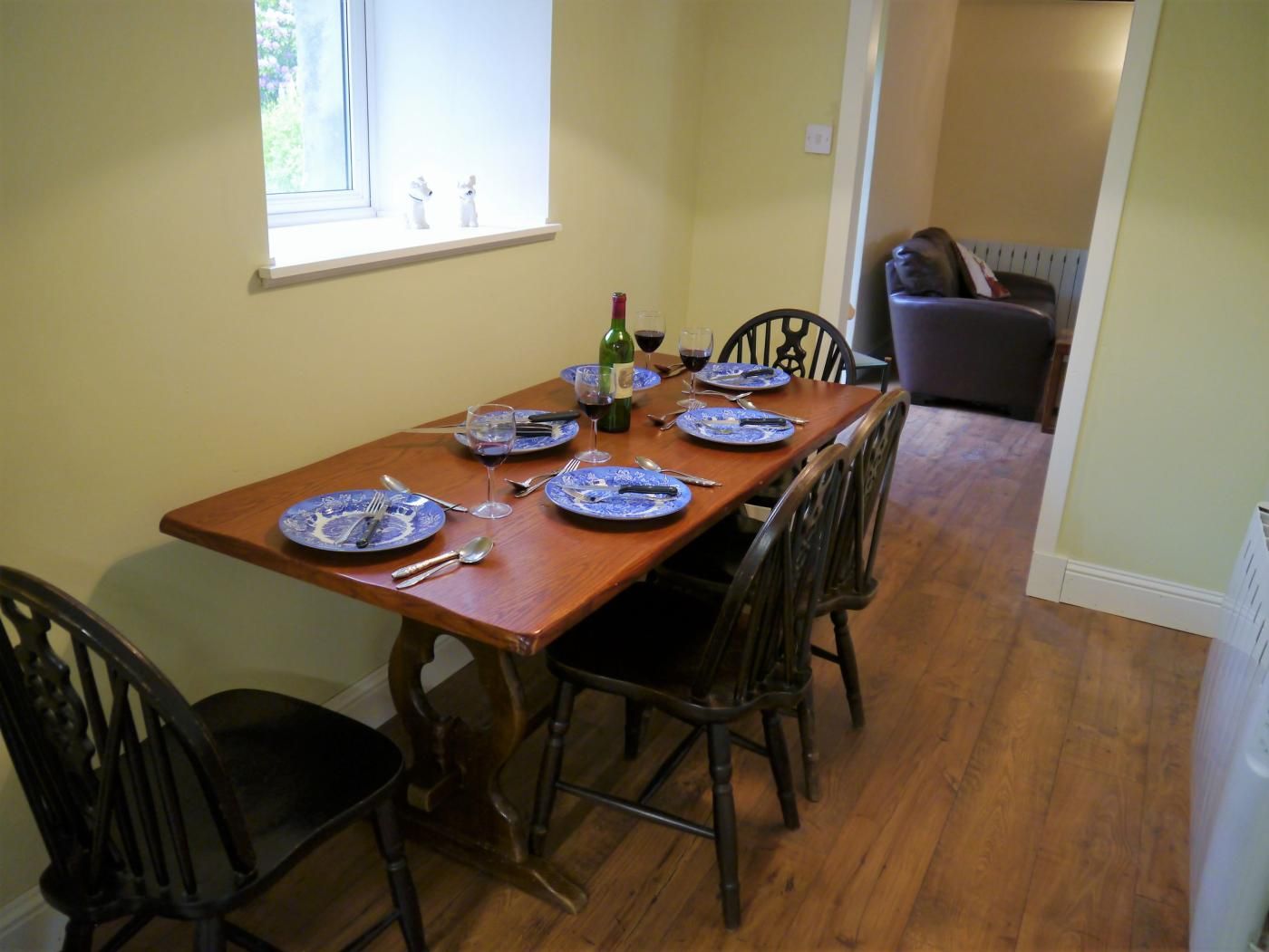 A dining table set with blue plates, silverware, and wine glasses.
