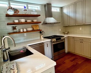 A kitchen with a stove, oven, and a sink. There are shelves above the counter holding dishes and a vase. - Walk to Plaza, 2BR/2.5BA Townhouse, Best for extended vacation, relocation, LANL (Santa Fe)