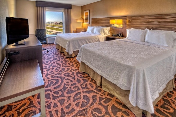 Quarto de hotel com duas camas, televisão e vista para o exterior.