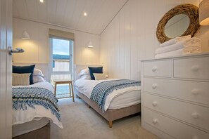 Une chambre avec deux lits, une commode, un miroir et une fenêtre.