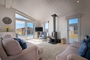 Un salon spacieux avec un haut plafond, une grande fenêtre, une cheminée et un téléviseur.