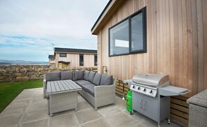 An outdoor patio with a sectional sofa, a dining table, and a barbecue grill. - 3 Bed in Mossyard, Gatehouse Of Fleet (oc-d555702) (Gatehouse of Fleet)