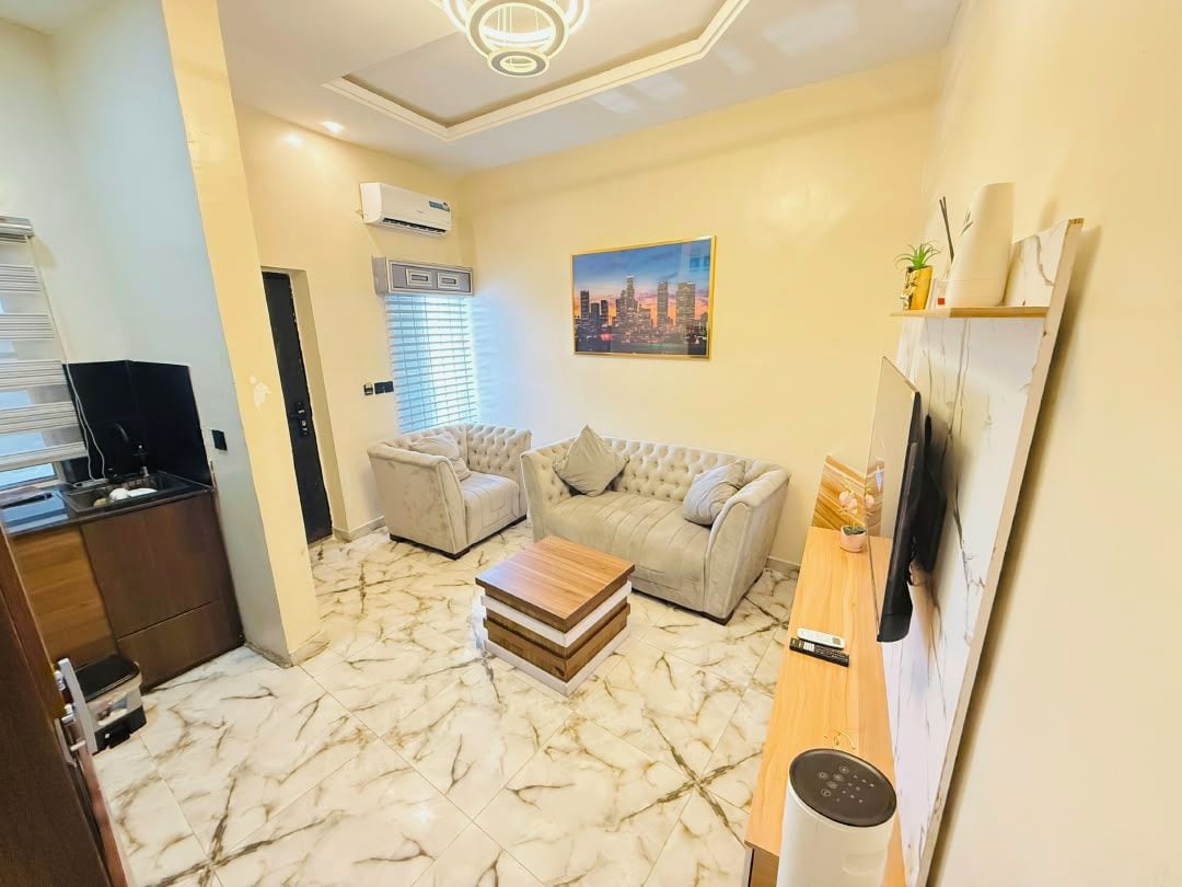 A compact living space with a sofa, a coffee table, a TV, and a kitchen area.