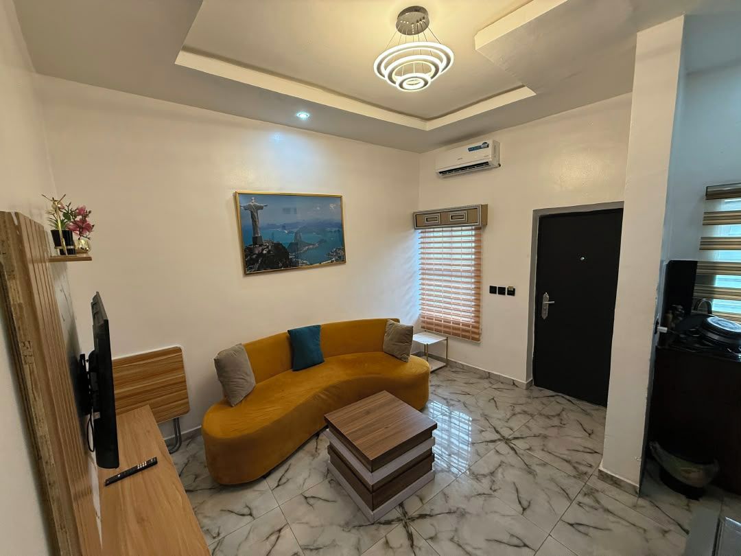 A modern living room with a sofa, a coffee table, a TV, and a painting of a cityscape.