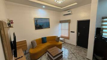 A modern living room with a sofa, a coffee table, a TV, and a painting of a cityscape.