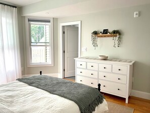 A bedroom with a bed, a dresser, a window, and a door. - Boston Urban Nests U4: Long Term 1 Month + (Boston)