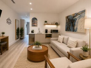A modern living room with a sofa, coffee table, and a kitchen area in the background. - Enjoyable 1-bedroom apartment in peaceful Miami neighborhood (Miami)