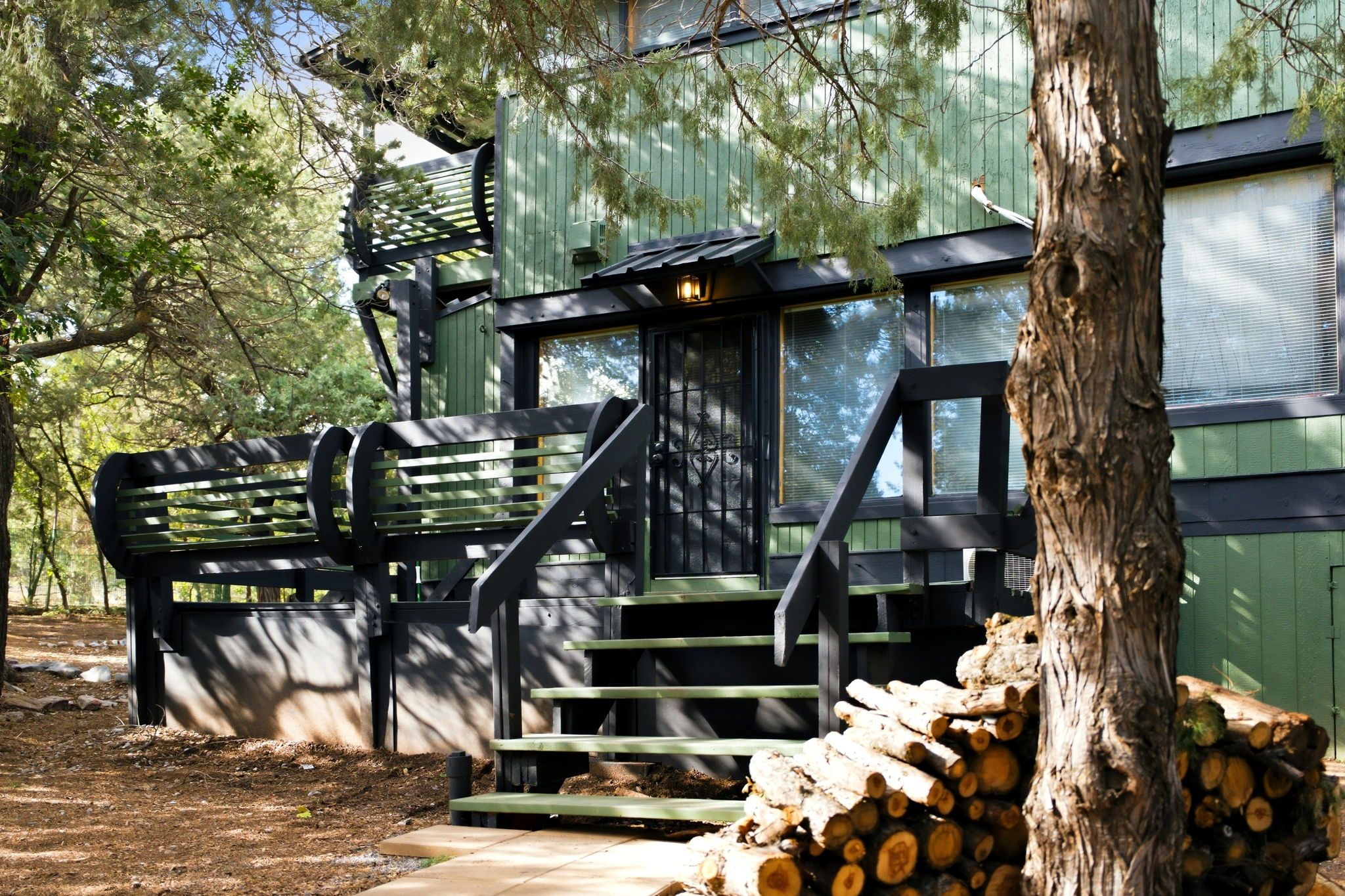 Eine Holzhütte mit einer Treppe, die zu einer Terrasse führt, umgeben von Bäumen.