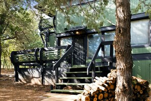 A wooden cabin with a staircase leading to a deck, surrounded by trees. - Premium Cabana - Outdoor Jacuzzi (Tijeras)