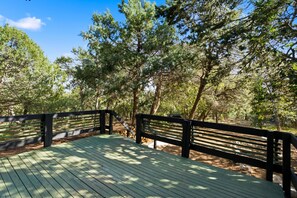 A wooden deck with railings, surrounded by trees. - Premium Cabana - Outdoor Jacuzzi (Tijeras)