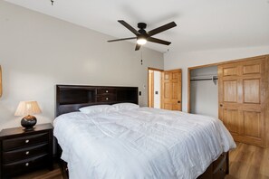 A bedroom with a bed, a nightstand, a lamp, a ceiling fan, and wooden doors. - Premium Cabana - Outdoor Jacuzzi (Tijeras)