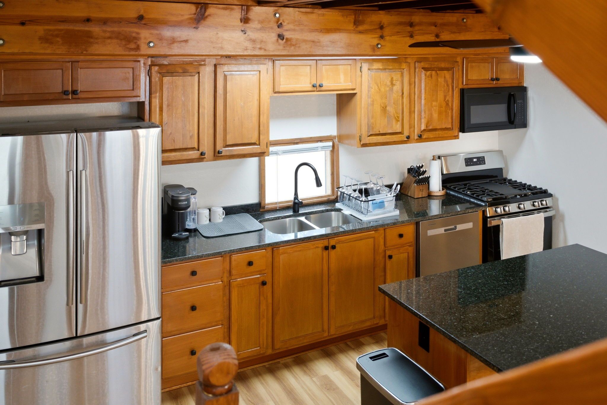A kitchen with wooden cabinets, stainless steel appliances, a sink, and a stove.